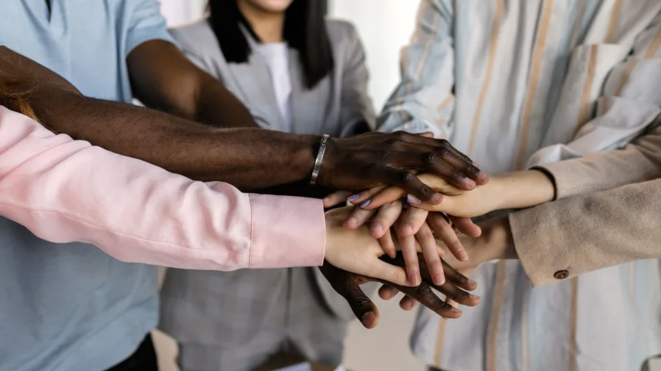 Hands of a diverse team stacked together in a circle